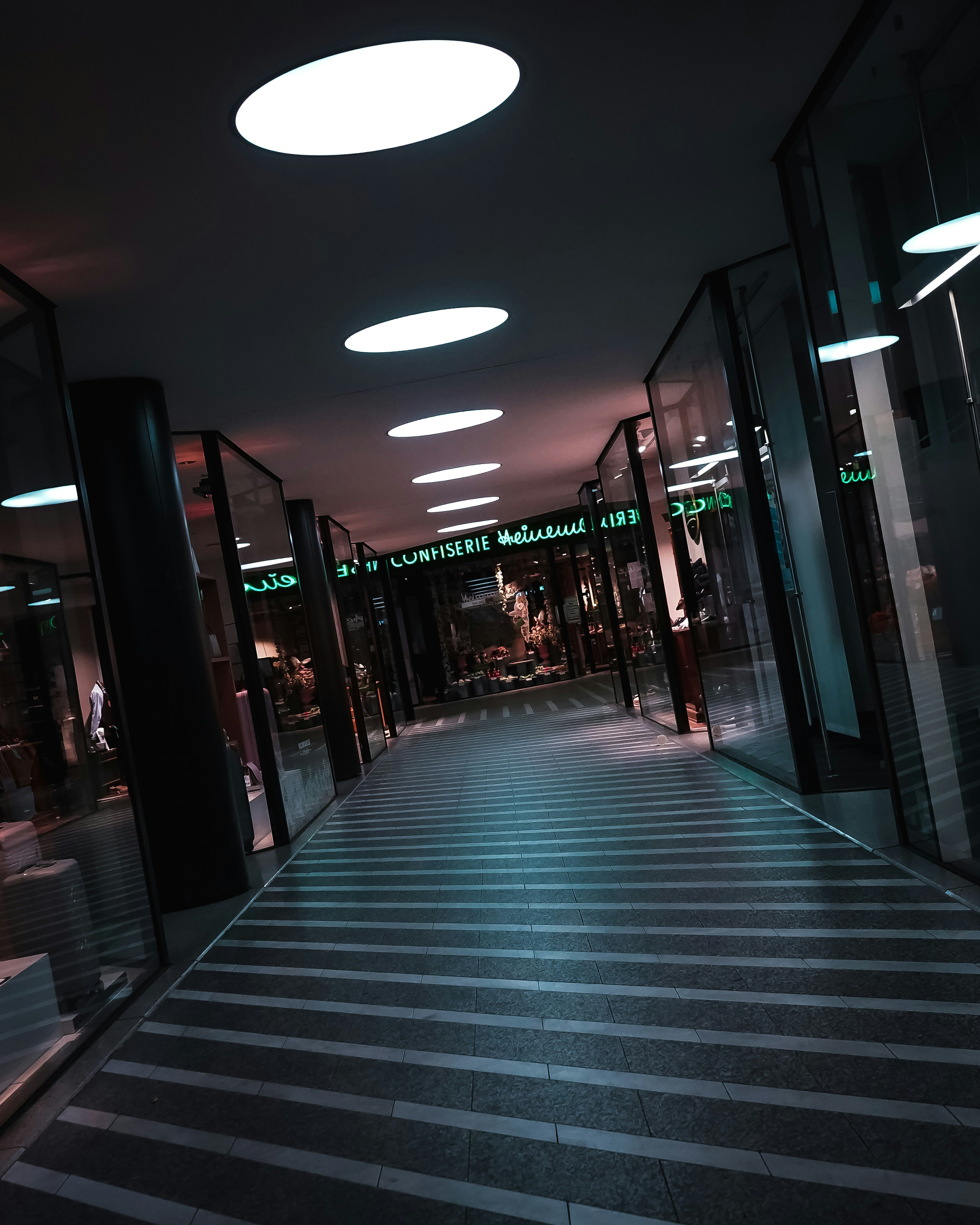 A quiet, dimly lit corporate corridor lined with glass walls receding into the distance