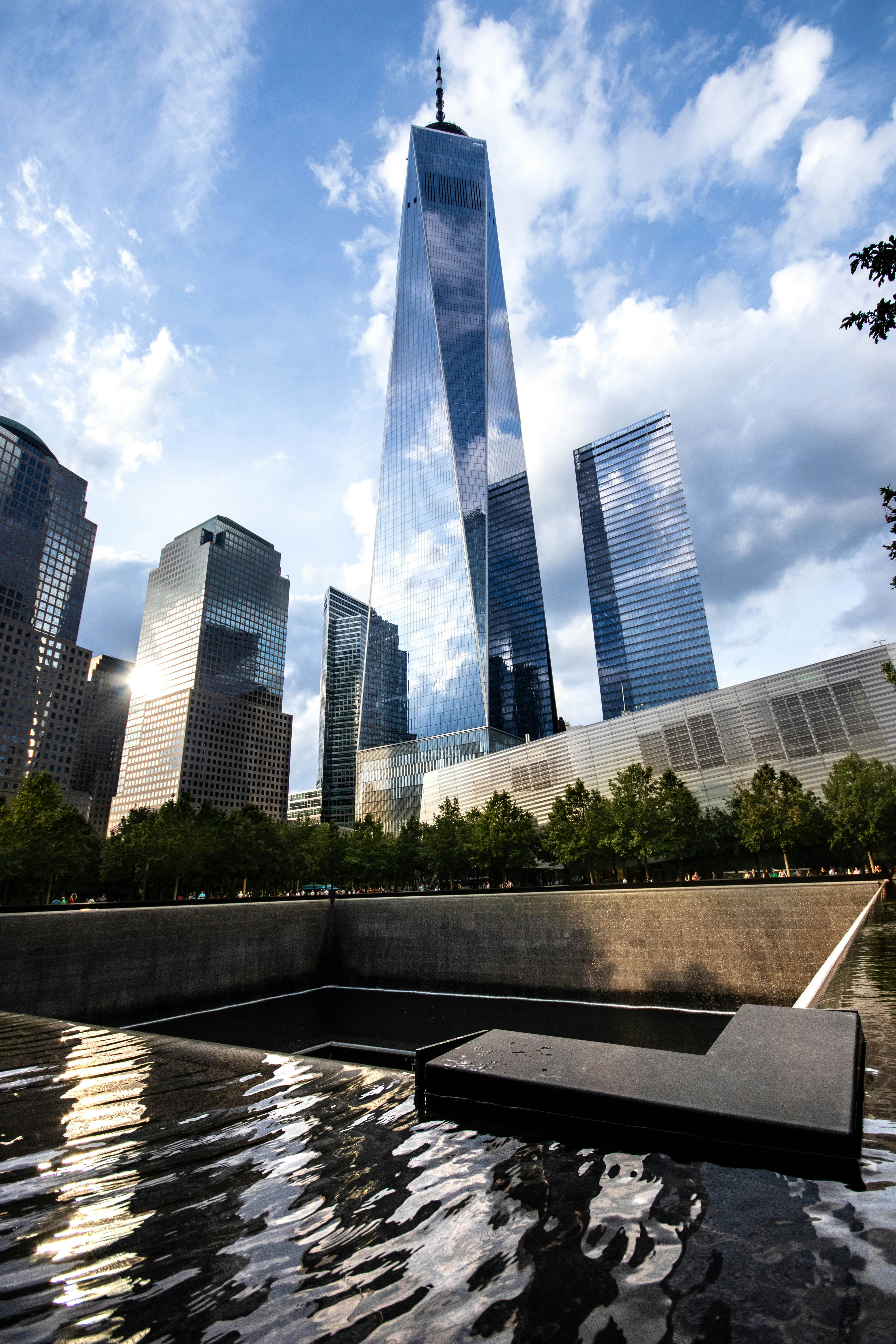 The 9/11 Memorial reflecting pool with One World Trade Center rising into the sky behind it